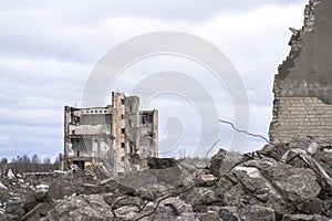 A pile of large gray concrete fragments with protruding fittings against a cloudy sky