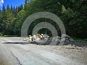 A pile of large stones, parts of rocks that lie on the edge of the forest by the asphalt road