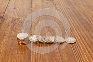 A pile with a lot of Real brazilian money coins stacked on a wood table