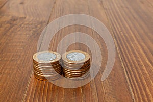 A pile with a lot of Real brazilian money coins stacked on a wood table