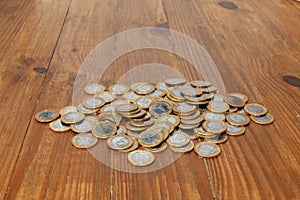 A pile with a lot of Real brazilian money coins on a wood table