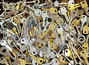 Pile of many different yellow and white old metal keys choice to open a door