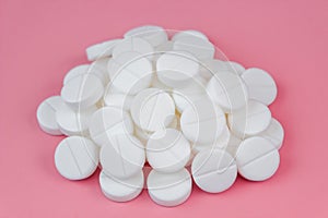 A pile of medical pills on a pink background close-up. The concept of pharmacology, treatment of diseases