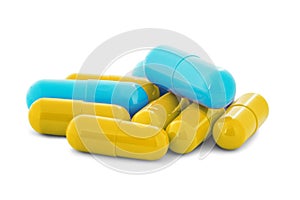 Pile of medical pills in yellow and blue colors on white isolated background with shadow