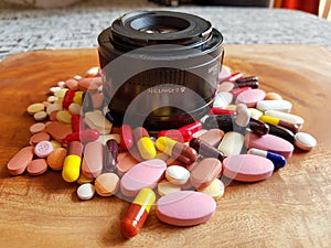 Pile of medicine pills tablets capsules around lens in wooden background