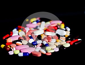 Pile of medicine pills tablets capsules in black background