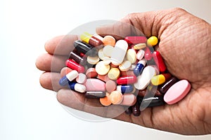 Pile of medicine pills tablets capsules in a palm in white background