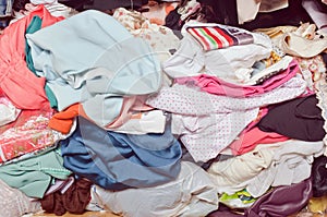 Pile of messy clothes in closet. Untidy cluttered woman.
