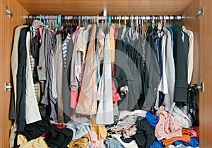 Pile of messy clothes in closet. Untidy cluttered woman wardrobe