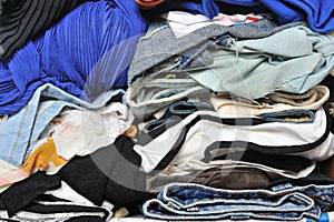 Pile of messy multicolor clothes in closet. Untidy cluttered woman