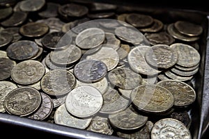 Pile of metal coins of different denominations and different countries in metal box