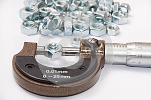 Pile of metal nuts and analog micrometer