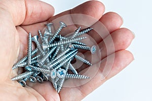 Pile of metal screws in the human palm