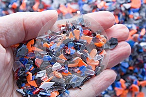 A pile of microplastics - small pieces of hard plastic on palm, intended for further processing.