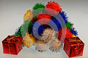 A pile of multi coloured pom poms with a wrapped present in the front