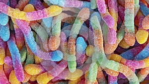 Pile of neon sugary gummy worms or  chewy sour crawlers background