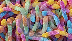 Pile of neon sugary gummy worms or  chewy sour crawlers background