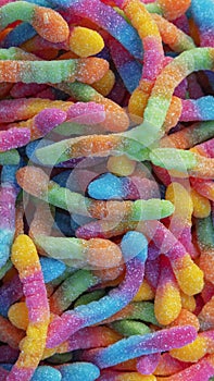 Pile of neon sugary gummy worms or  chewy sour crawlers background