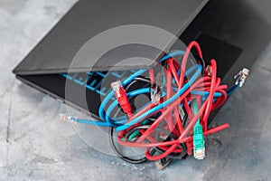 A pile of network wires and a laptop on the table, a concept on the difficulty of connecting to a local network or the Internet