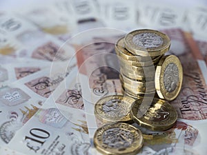 Stack of new pound sterling coins on semi circle of ten pound notes