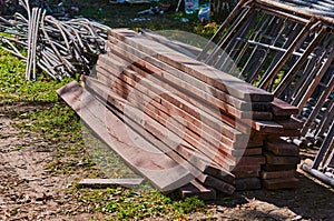 A pile of new lumber and a stack of stacked building steel structures on a construction site with grass.