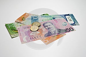 Pile of New Zealand dollars and  coins  in detail on white