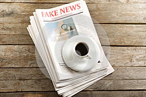 Pile of newspapers and cup of coffee on wooden background