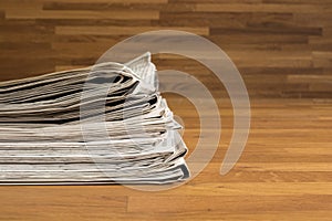 A pile of Newspapers on a wooden table