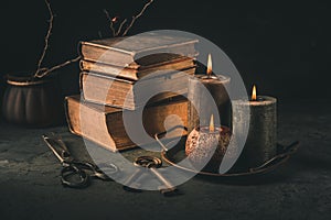 Pile of old antique books with candle and old rusty keys in vintage style
