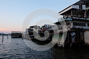 A pile of old Asian shacks on the banks of the Chao Phraya River. Sunset on a background of Asian slums