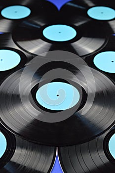 Pile of old black vinyl records on blue background