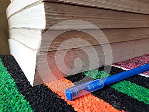 Pile of old books with writing pen near it on study table