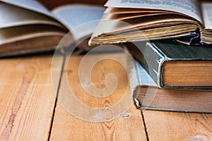 Pile of old closed and open books on aged wood backgound, negative space for text