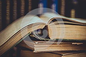 Pile of old opened books, row of volumes in the background, vintage style, education, reading concept, toned