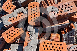 A pile of old red bricks with the remains of dried mortar. Building material red brick with holes.
