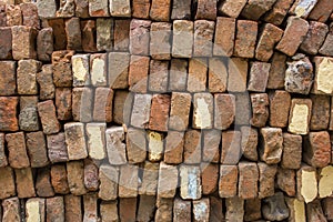 Pile of old red bricks stacked in even rows. rough surface texture