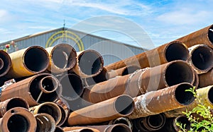 Pile of old rusty round metal industrial pipe. Steel pipe stack at warehouse of factory. Industrial material. Metal corrosion.