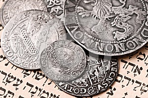 Pile of old silver coins on open Siddur page. Selective focus. Closeup