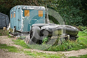 A pile of old tyres in front of an abandoned caravan