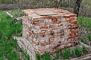 A pile of old used bricks lies on the ground among green young grass in spring