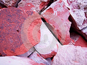 Pile of old used bricks, red bricks with plaster remnants, construction waste, broken bricks