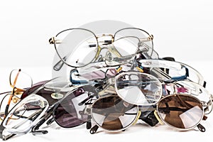 Pile of old used eye reading spectacles glasses on a white background. In studio