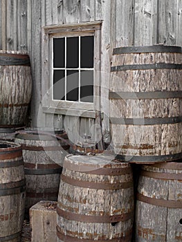 Pile of old wooden barrels by a wall.