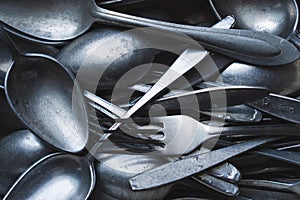 Pile of old worn vintage cutlery. Background of aluminium forks and spoons. Top view
