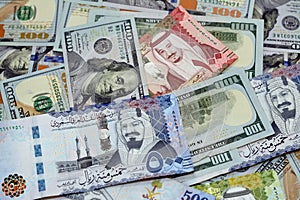 Pile of 100 $ one hundred dollar bills American cash money banknotes with Saudi Arabia riyals money banknotes