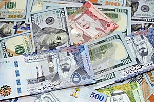 Pile of 100 $ one hundred dollar bills American cash money banknotes with Saudi Arabia riyals money banknotes of 500 riyals