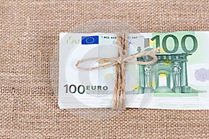 Pile of one hundred euro banknotes tied with rope