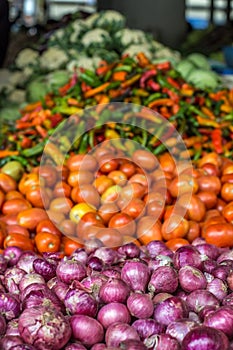 Pile of onions next to a pile of tomatoes and peppers