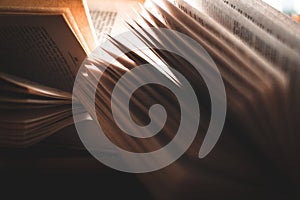 A pile of open paperback books back lit by window light