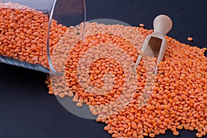 Pile of oranage lentils poured out from glass cup.